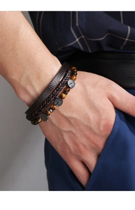 Close-up of tiger eye beads and leather bracelets featuring Tree of Life metal charms