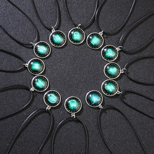 Set of 12 luminous zodiac necklaces with glowing green galaxy pendants on black wax ropes