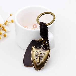Vintage bronze shield cross leather keychain on a clean minimalist background