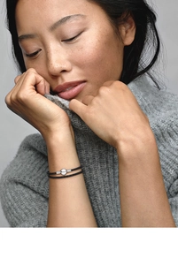 Close-up of double-wrap black braided leather bracelet with a silver spherical clasp on wrist