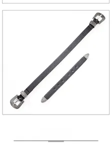 Détail d'une ceinture noire texturée avec boucle et bout en métal argenté ciselé