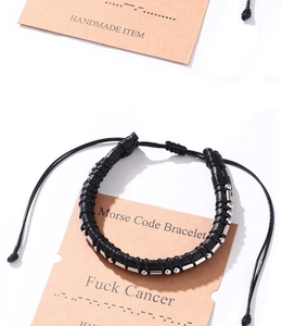 Macro shot of Morse code woven bracelet with stainless steel beads on packaging card