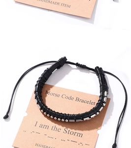 Detail of Morse Code braided bracelet with silver beads on branded display card
