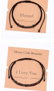 Detail of handmade Morse code bracelets with wood and metal beads on a brown card