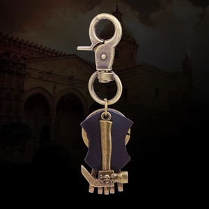 Vintage bronze hammer keychain with leather strap and skull relief on dark background