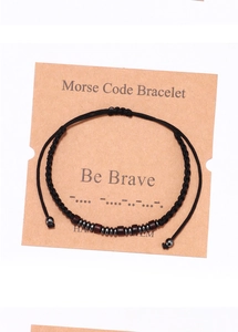 Close-up of handmade Morse code bracelet with wood beads on Be Brave gift card