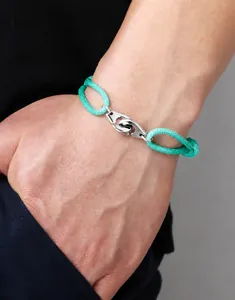 Detail of green woven rope bracelet featuring a polished stainless steel handcuffs clasp