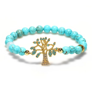 Vue détaillée des perles de turquoise et du pendentif arbre de vie doré sur le bracelet