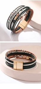 Detalle de pulsera bohemia de cuero con dijes de hojas y cierre magnético fuerte
