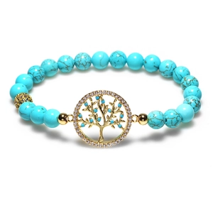 Bracelet en perles turquoise avec pendentif arbre de vie et accents dorés sur fond blanc