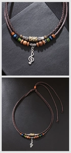 Close-up of vintage beaded necklace featuring a silver treble clef music note pendant