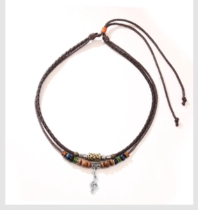 Macro detail of vintage beaded necklace with musical note pendant and woven rope
