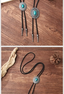 Close-up of vintage metal bolo tie with turquoise stone and floral engraving detail
