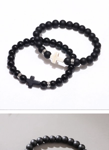Detail of matte obsidian and onyx beaded bracelets with cross charms and Greek pattern beads