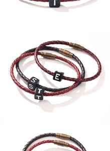 Détail de bracelets en cuir tressé avec fermoir magnétique bronze et perles lettres