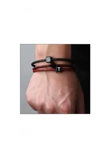 Gros plan de bracelets tressés en cuir avec charmes cubes noirs gravés S, E, T au poignet