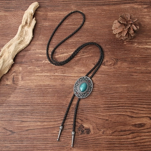 Vintage bolo tie with turquoise stone and silver-tone metal on dark wood background