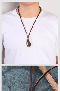 Close-up of vintage brown leather necklace with metal triangle pendant and stitching details