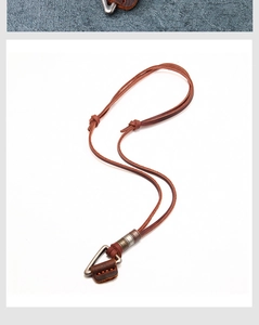Detail of leather cord necklace with vintage metal triangle pendant and orange stitching
