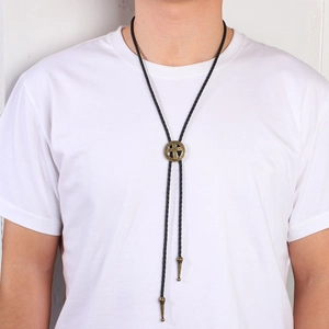 Vintage western bolo tie with bronze cross buckle and black braided rope on a white shirt