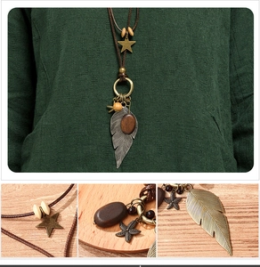 Detail of vintage bohemian necklace with metal feather, wooden charms and woven cord