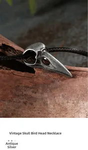 Macro shot of punk gothic crow skull pendant in vintage silver with braided leather cord
