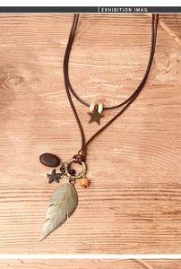Detail of vintage bohemian necklace with bronze feather, starfish, and star charms