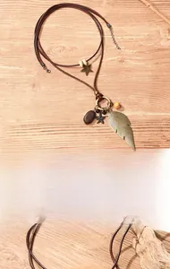 Detailed macro view of vintage layered necklace with feather and star pendants on brown leather cord