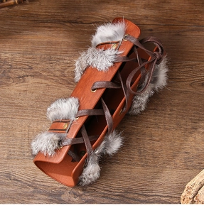 Detail of Viking leather bracer with rabbit fur trim and lacing on wood background