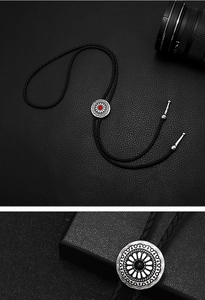 Close-up of vintage bolo tie with red gemstone and intricate floral metal engraving