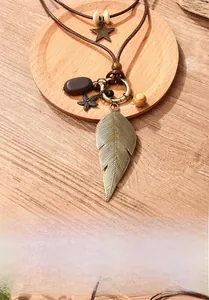 Detail of vintage bronze feather and starfish pendant necklace on rustic wooden base
