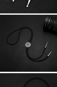 Macro detail of silver floral bolo tie with red stone on black textured leather