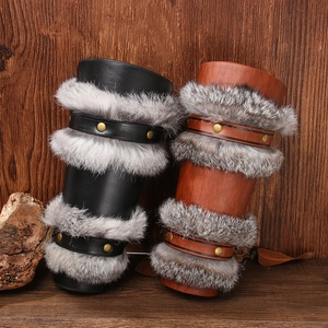 Viking leather bracers with rabbit fur trim in black and brown over wood background