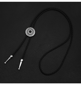Detail of silver sunburst bolo tie slide with black bead on woven leather cord