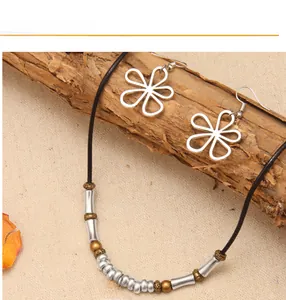 Parure de bijoux boho avec pendentifs floraux et perles sur fond de bois texturé