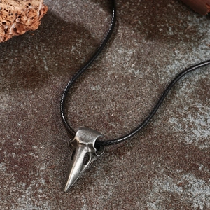 Gothic punk crow skull bird head pendant necklace with silver finish on stone background