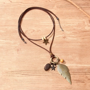 Vintage bohemian layered necklace with metallic leaf and star pendants on wax rope