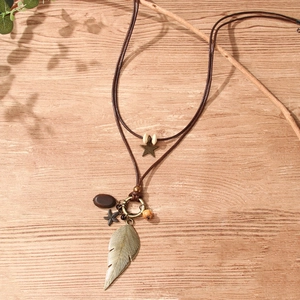 Vintage bohemian layered leaf and starfish pendant necklace on rustic wood surface