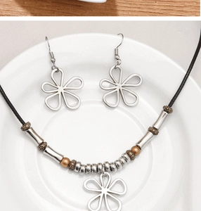 Détail du collier de perles trèfle argenté et boucles d'oreilles sur plateau céramique