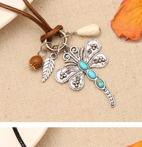 Macro shot of vintage silver dragonfly pendant with turquoise inlay and wooden beads decoration