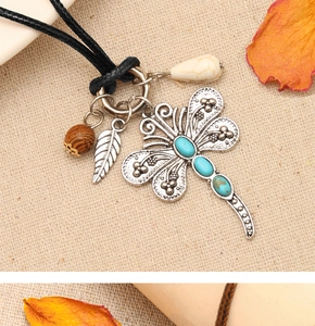 Detail of vintage dragonfly necklace with turquoise stones, feather, and wood beads