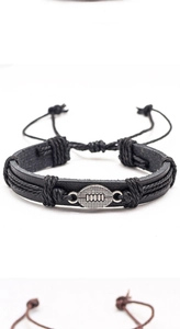 Detalle de pulsera de cuero trenzado negro con dije de metal en forma de balón de rugby