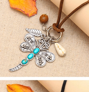 Macro shot of vintage dragonfly pendant with turquoise stones on brown woven cord