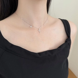 Gros plan d'un collier croix en argent S925 avec zircons porté par un mannequin femme