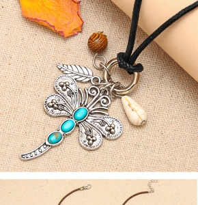 Detailed view of dragonfly pendant with turquoise stones on rustic linen background