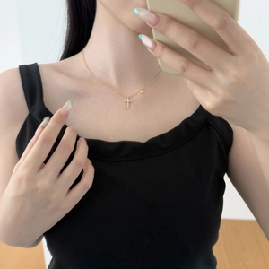 Gros plan d'un collier croix doré délicat serti de zircons porté par un mannequin