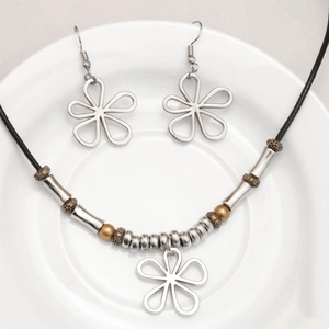 Ensemble collier et boucles d'oreilles trèfle sur une assiette en céramique blanche