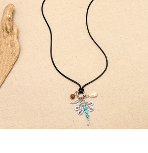 Detailed shot of ethnic dragonfly pendant with turquoise gems and small shell charms