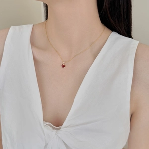 Close-up of elegant gold chain necklace with heart-shaped red agate pendant on collarbone