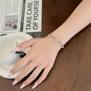Détail d'un bracelet minimaliste en argent S925 avec breloque cœur et cordon gris